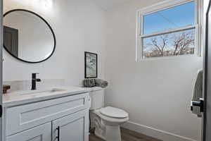 Half bath featuring vanity and dark wood-type flooring