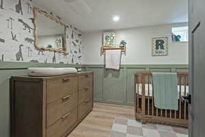 Bathroom featuring vanity, light wood finished floors, a wainscoted wall, and recessed lighting