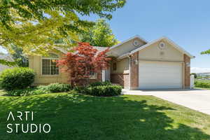 View of front of home with an attached garage, brick siding, driveway, and a front yard