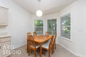 Dining space featuring light carpet, plenty of natural light, and lofted ceiling