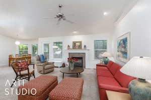 Carpeted living area with a fireplace and a ceiling fan