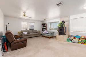 Living room with carpet flooring, a wood stove, and ceiling fan