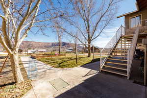 View of green lawn with a mountain view and a patio area