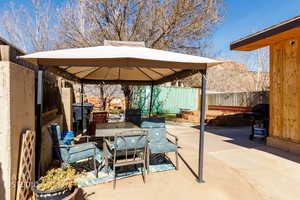 Fenced backyard with a gazebo, outdoor dining space, a patio area, and area for grilling
