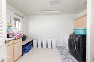 Laundry room featuring cabinet space, light flooring, and washing machine and clothes dryer