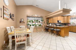 Dining area with vaulted ceiling and light tile patterned flooring