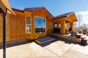 Property entrance featuring a patio area and a shingled roof