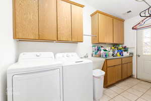 Laundry room featuring independent washer and dryer, cabinet space, and light tile patterned floors