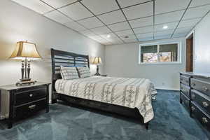 Bedroom with dark colored carpet, a paneled ceiling, and recessed lighting
