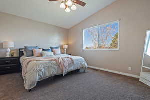 Bedroom with dark carpet, vaulted ceiling, and ceiling fan