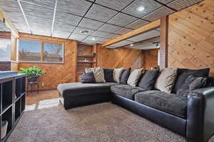 Carpeted living room featuring wooden walls and recessed lighting