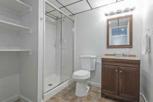 Bathroom featuring vanity, a stall shower, stone finish flooring, and a paneled ceiling
