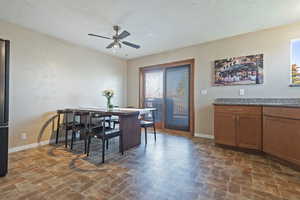 Dining space featuring ceiling fan and brick patterned floors