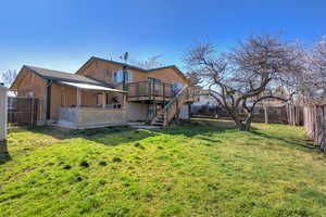 Rear view of house featuring a fenced backyard, a deck, and a patio area