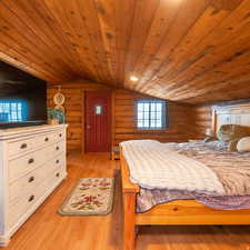 Bedroom featuring log walls, a vaulted wood ceiling, and light wood finished floors