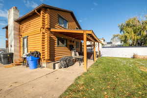 Back of property featuring log exterior, a chimney, and a patio area