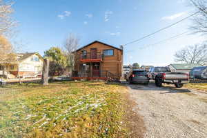 View of front of house featuring log veneer siding, a deck, driveway, and a front lawn