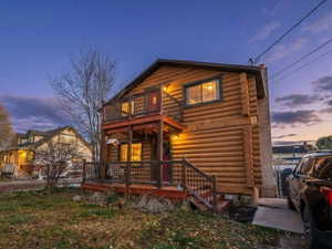 View of front of home with log siding and a balcony