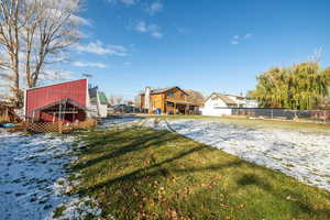 Yard covered in snow with a patio, a residential view, and an outbuilding