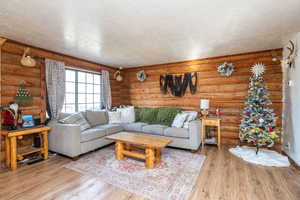 Living room featuring rustic walls, a textured ceiling, and light wood-type flooring