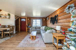 Living area with log walls, a textured ceiling, and wood finished floors