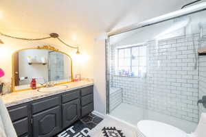 Bathroom with a shower stall, vanity, and dark tile patterned floors