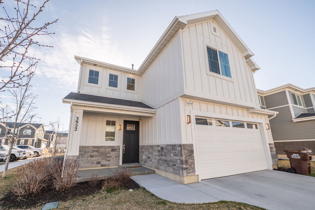Modern farmhouse style home with board and batten siding, an attached garage, concrete driveway, and covered porch