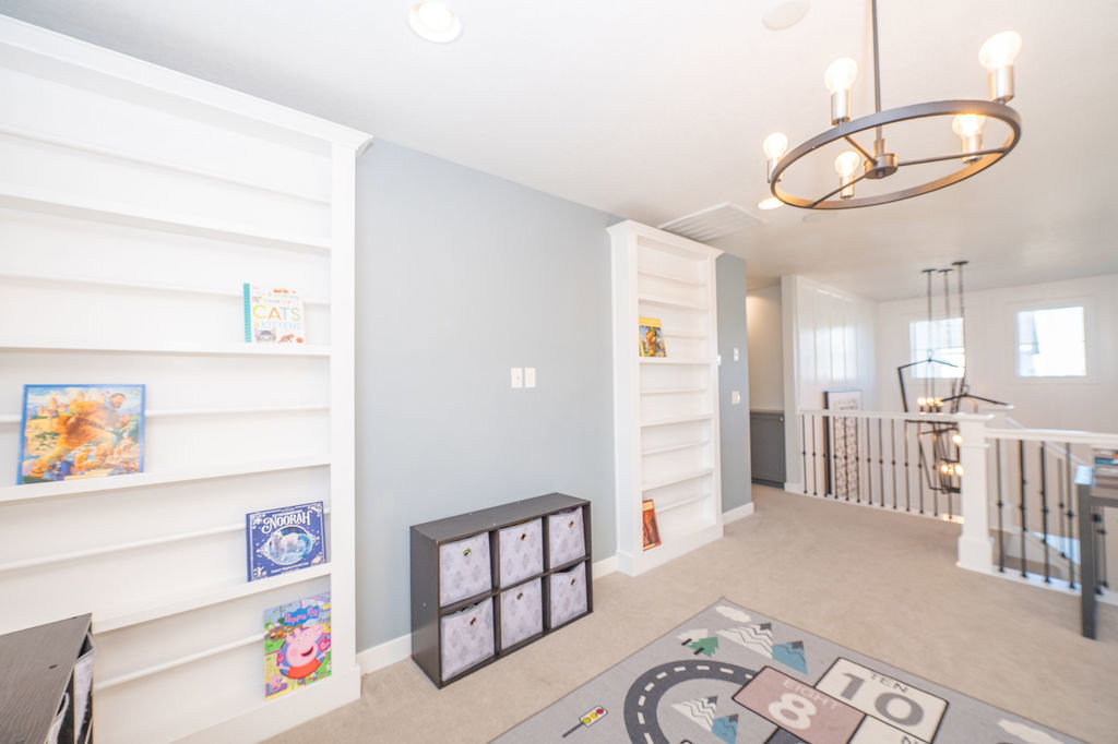 Playroom with suspended lighting, light carpet, and built in shelves