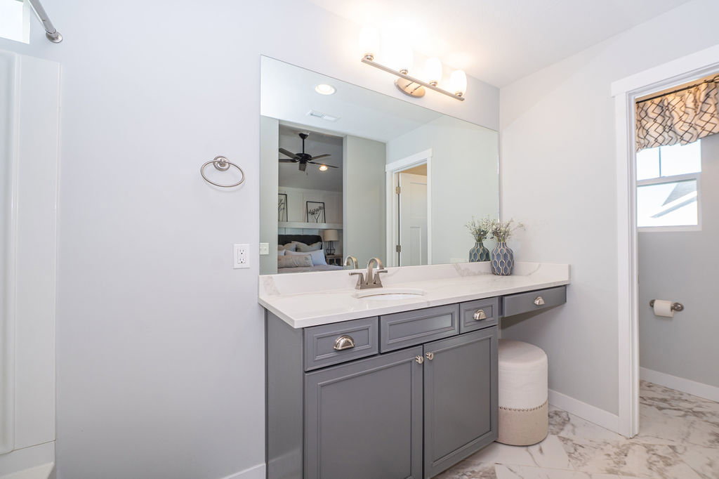 Ensuite bathroom featuring vanity, light marble finish floors, and a ceiling fan