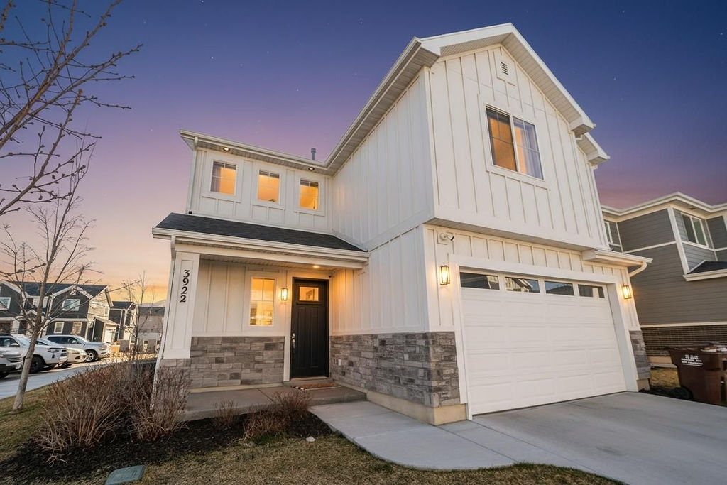 Modern inspired farmhouse featuring board and batten siding, an attached garage, and driveway