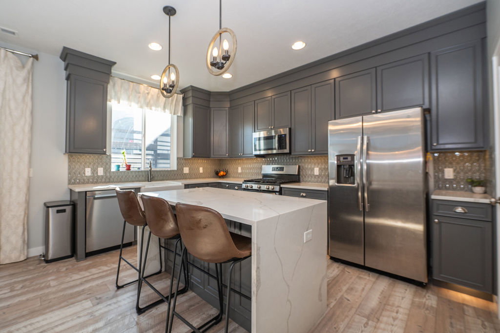 Kitchen with stainless steel appliances, a kitchen breakfast bar, a center island, light stone countertops, and light wood-type flooring
