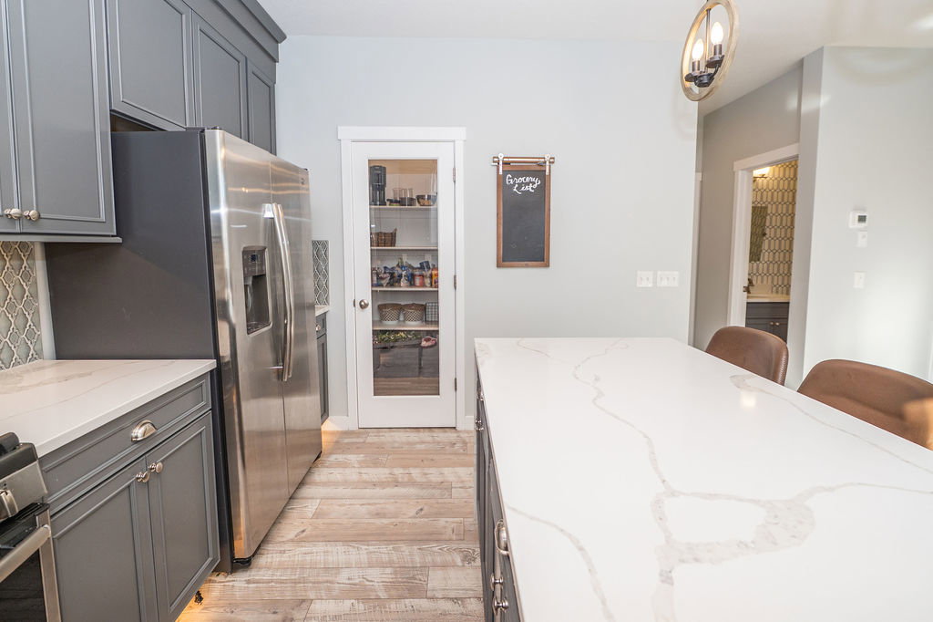 Kitchen featuring gray cabinets, light stone counters, stainless steel appliances, a kitchen bar, and light wood-type flooring