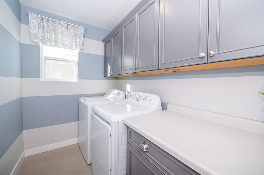 Laundry room with washing machine and clothes dryer, cabinet space, and light tile patterned flooring