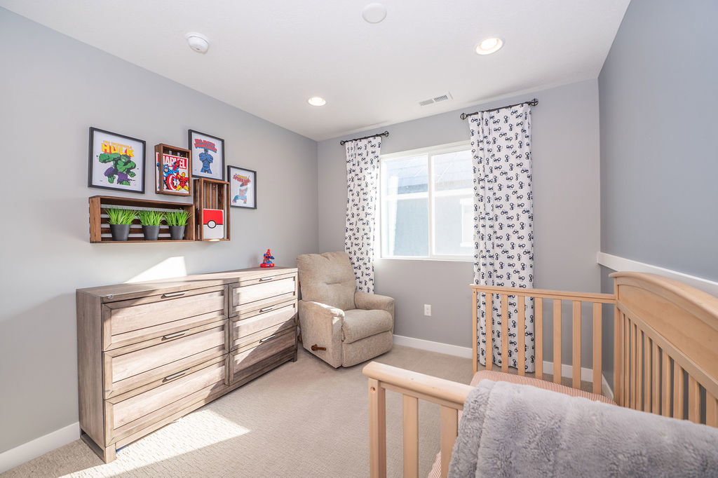 Bedroom featuring light colored carpet, a nursery area, and recessed lighting