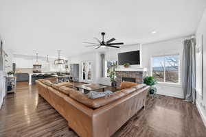 Living area with a fireplace, dark wood-style floors, a ceiling fan, and hanging lights