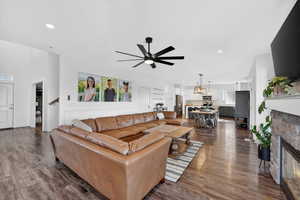 Living area featuring a fireplace, ceiling fan, dark wood-type flooring, and recessed lighting