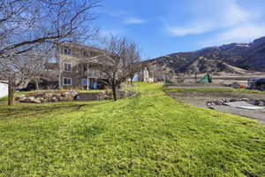 View of grassy yard featuring a mountain view and a patio