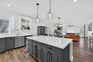 Kitchen with stainless steel dishwasher, dark wood-style floors, decorative light fixtures, and two tone cabinets