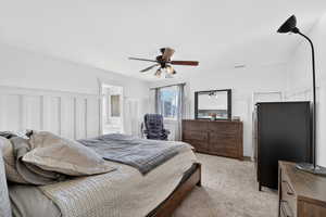 master Bedroom featuring a ceiling fan, light carpet, a wainscoted wall, ensuite bathroom, and a decorative wall