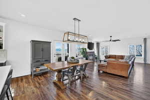 Dining room with dark wood finished floors, plenty of natural light, and a chandelier