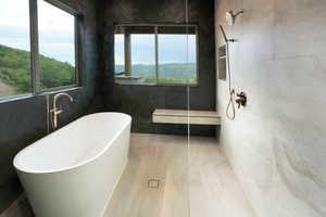 Bathroom with tile walls, a freestanding bath, and a walk in shower