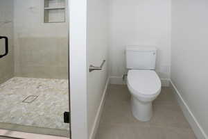 Full bathroom featuring a shower stall and light tile patterned floors