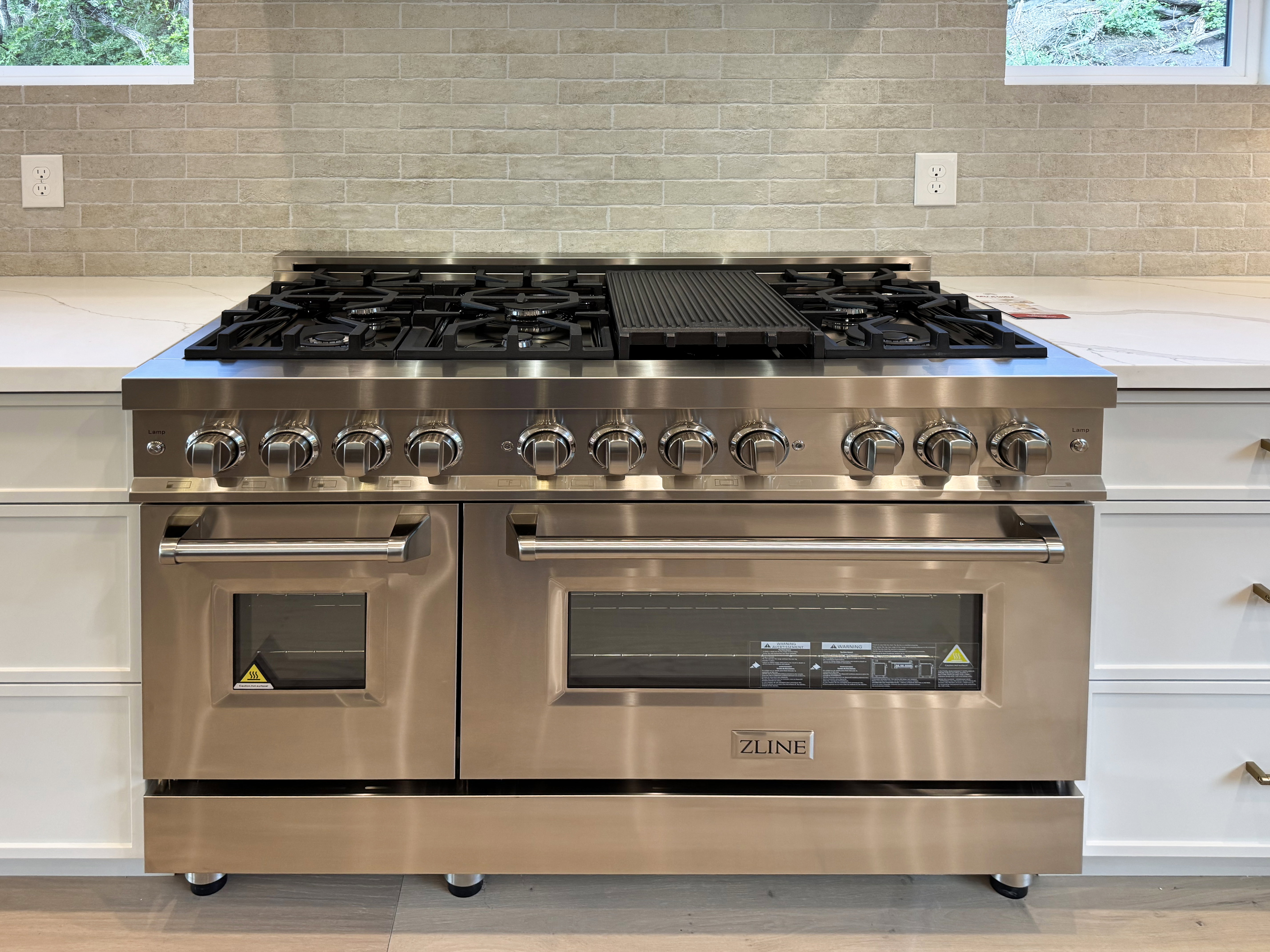 Kitchen view of range with two ovens, white cabinets, light stone countertops, and decorative backsplash