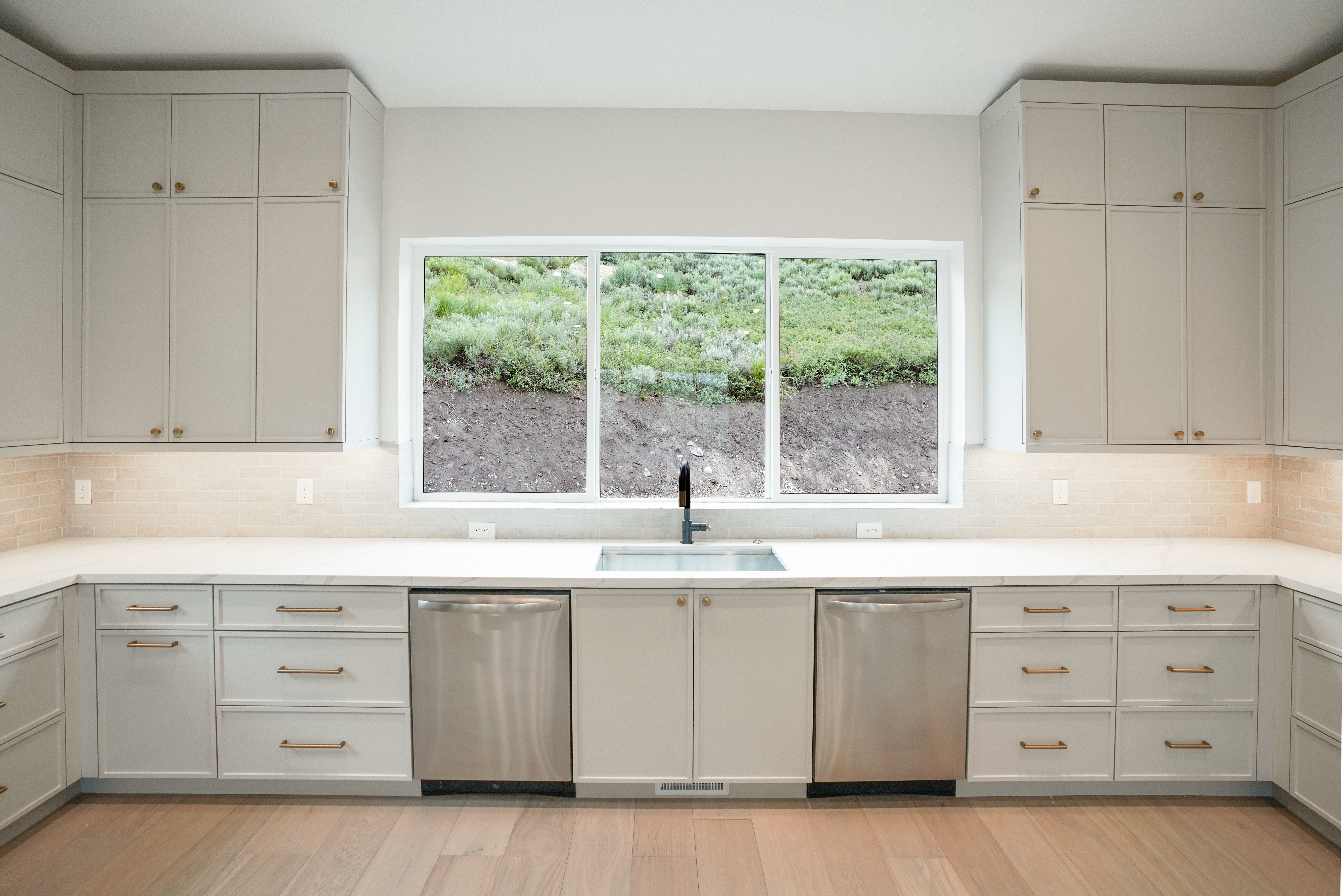 Kitchen with dishwasher, tasteful backsplash, light wood finished floors, and light stone countertops