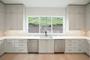 Kitchen with dishwasher, tasteful backsplash, light wood finished floors, and light stone countertops