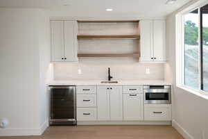 Bar featuring open shelves, beverage cooler, white cabinetry, tasteful backsplash, and recessed lighting