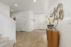 Foyer with light wood finished floors and recessed lighting