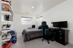 Bedroom featuring light carpet and an office area