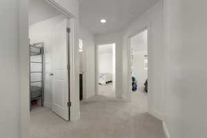 Hall with light colored carpet and baseboards