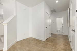 Hallway with light wood finished floors and recessed lighting
